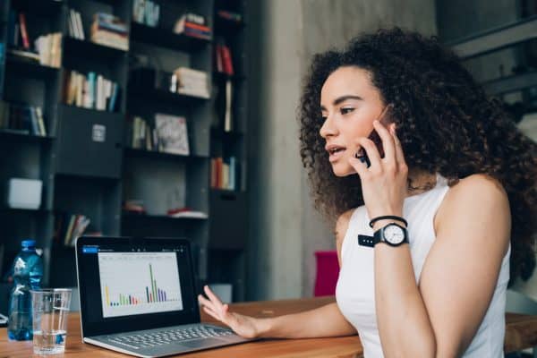 young brunette woman having business call about declining a request at work and working in modern office with laptop 